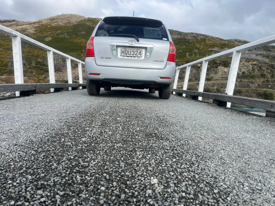 From behind on a one-lane bridge, hills ahead