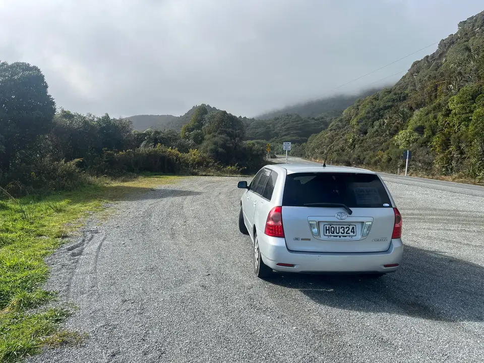 Seen from behind on a gravel turnaround below misty hills