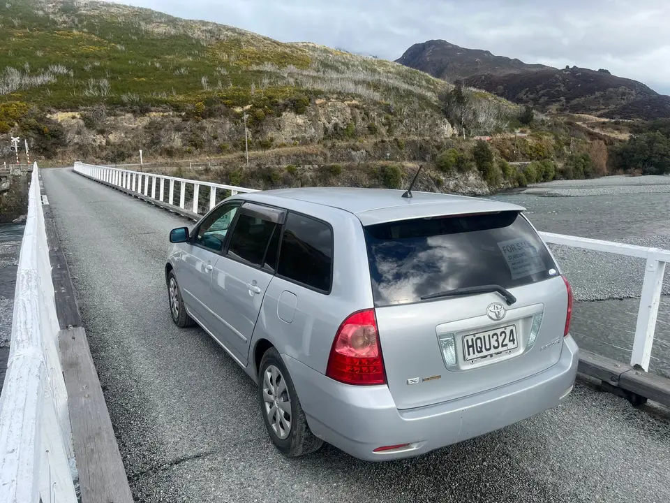 On a one-lane bridge below tussock hills