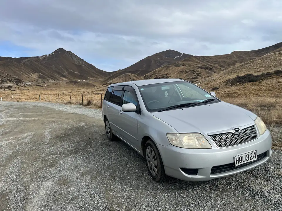 Parked on a gravel pull-off below dry tussock hills