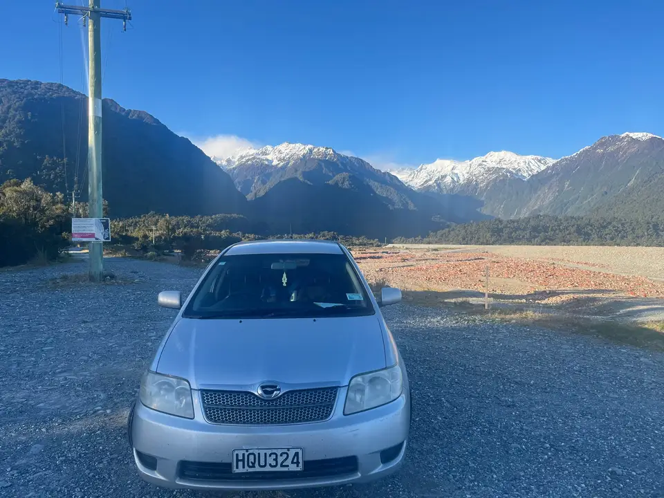Parked on river flats below snow-capped mountains