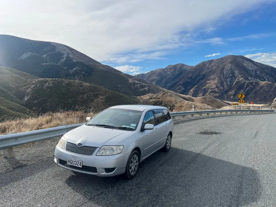 Parked on a highway bend below steep hills
