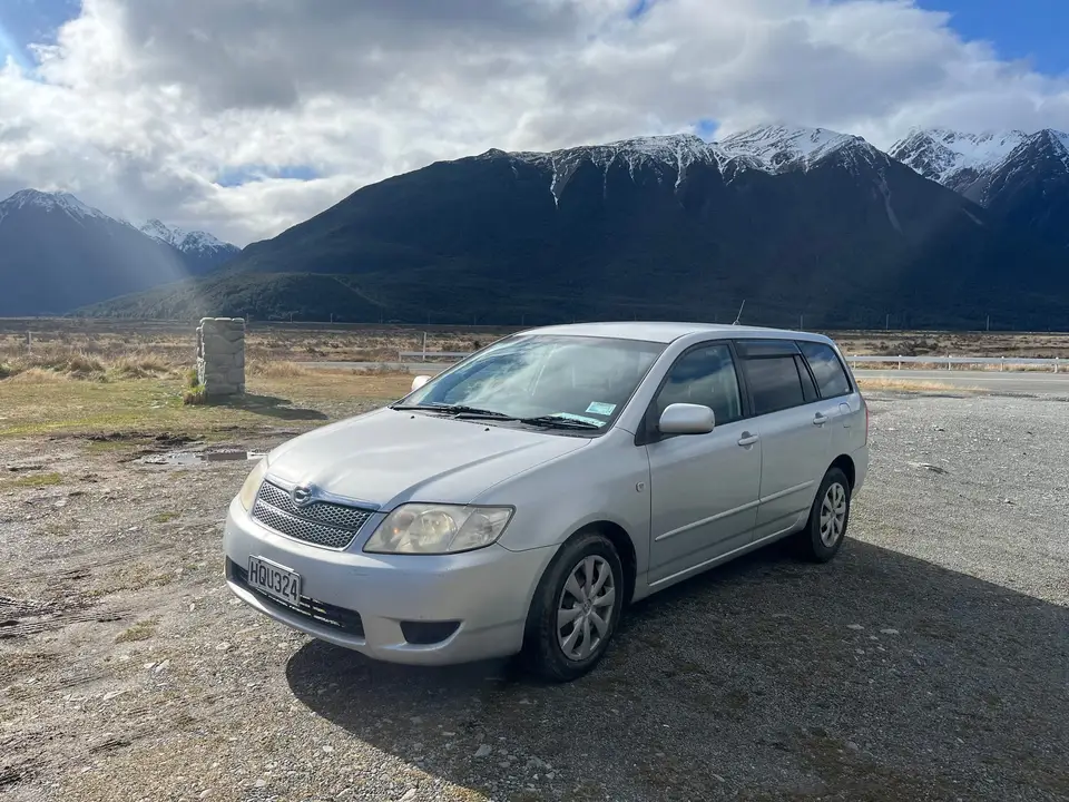 Parked on gravel flats below snow-capped mountains