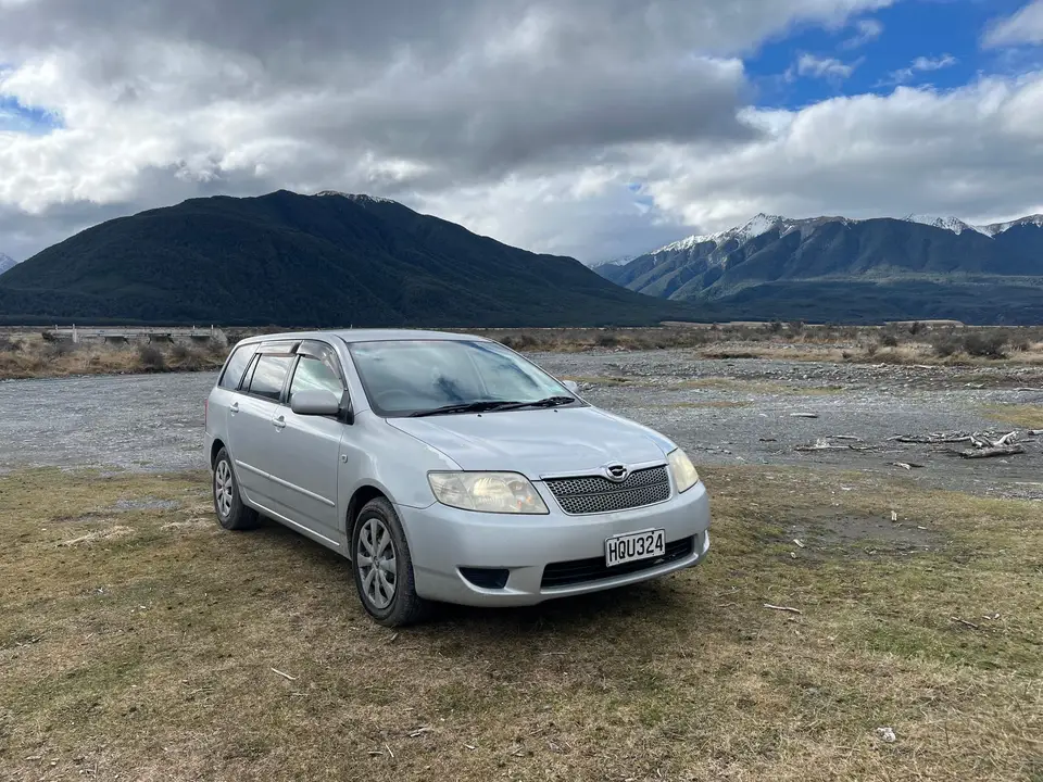 Parked on a braided riverbed with the mountains behind