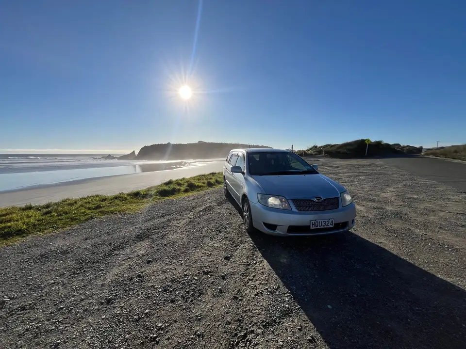 Parked above a West Coast beach with the sun low over the sea