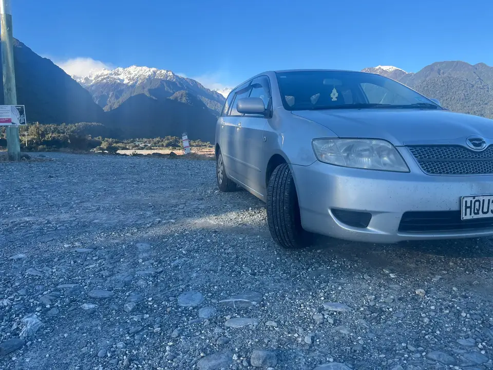 Parked on gravel below snow-capped peaks